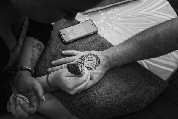 Henna artist painting bespoke henna on mans hand