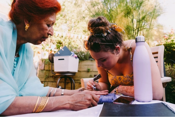 Henna artist painting henna on lady